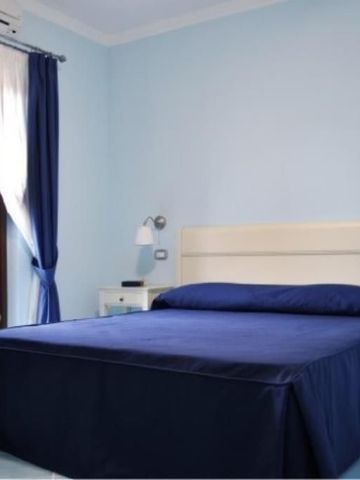 Schlafzimmer mit dunkelblauer Bettwäsche und hellem Mobiliar