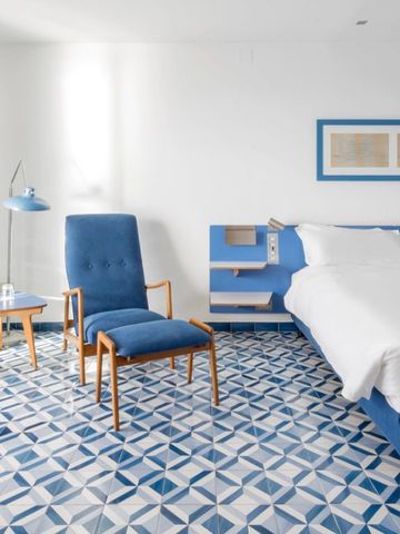 Modernes Zimmer mit blauem Sessel und geometrischem Teppichmuster
