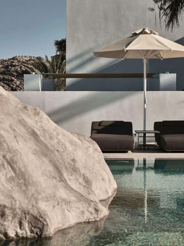 Poolbereich mit Liegen und Sonnenschirm neben Felsen