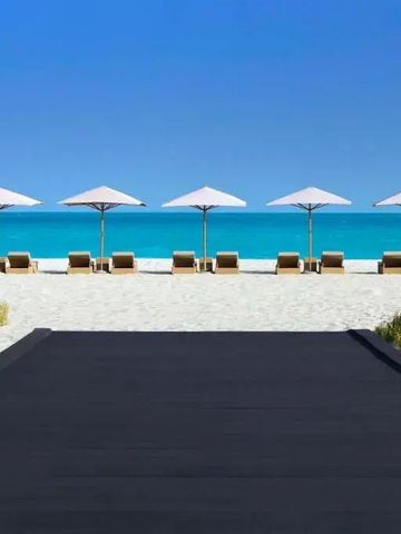 Strand mit Liegen und Sonnenschirmen am türkisfarbenen Wasser