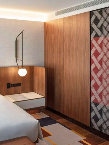 Elegantes Hotelzimmer mit Holzelementen und geometrischem Wandteppich