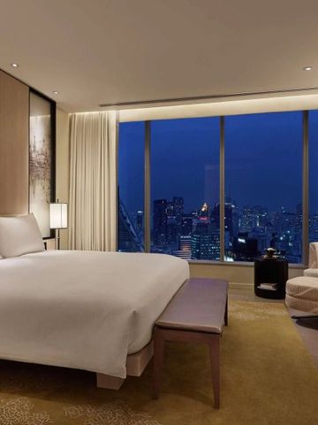 Elegantes Schlafzimmer mit großem Fenster und nächtlichem Blick auf die Stadt