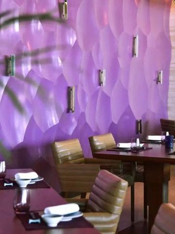 Stilvoll eingerichtetes Restaurant mit lilafarbener Wanddekoration