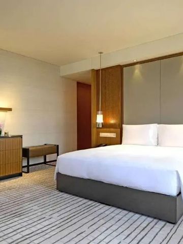 Geräumiges Hotelzimmer mit großem Bett, Holzmöbeln und schickem Teppich