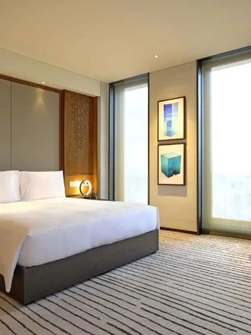 Helles Hotelzimmer mit großem Bett, modernen Kunstwerken an der Wand