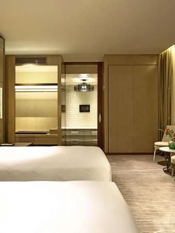 Elegantes Hotelzimmer mit zwei großen Betten und modernen Möbeln.