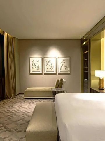 Geräumiges Hotelzimmer mit Kunstwerken an der Wand und gemütlicher Sitzecke.