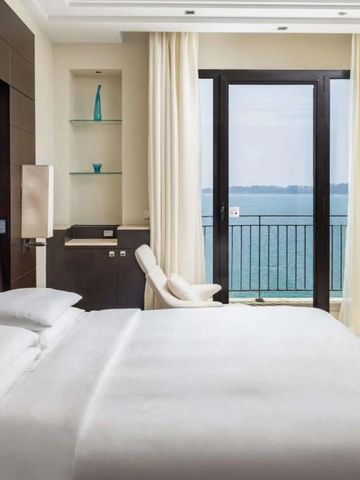 Geräumiges Hotelzimmer mit Bett und Meerblick durch große Fenster