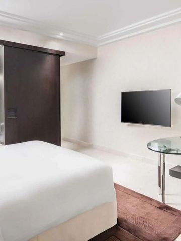 Modernes Hotelzimmer mit Glas-Schreibtisch und Wandkunst