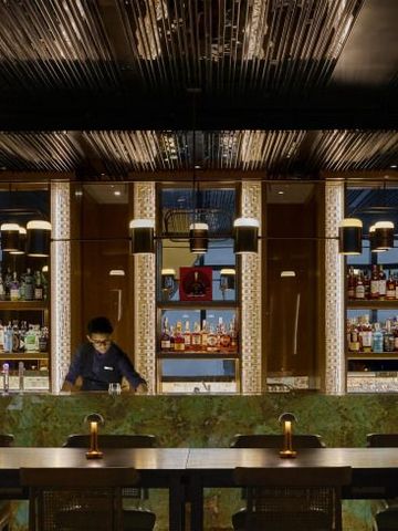 Elegante Bar mit beleuchtetem Tresen und umfangreicher Spirituosenauswahl