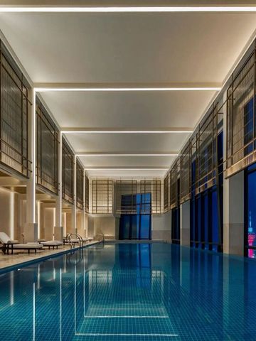 Innenpool mit hohen Decken und moderner Beleuchtung. Panoramafenster bieten Stadtansicht