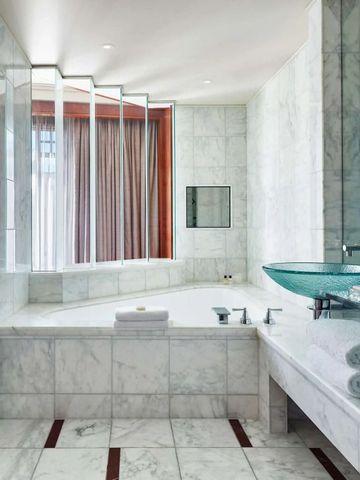 Moderne Badewanne mit Marmorwänden und Glaswaschbecken