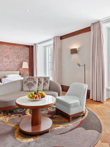 Großzügige Suite mit Sitzecke, runden Teppichen und großen Fenstern