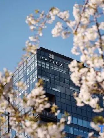 Nahaufnahme des Patina Osaka Hotels mit blühenden Zweigen im Vordergrund