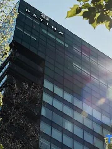 Fassade des Patina Osaka Hotels mit Sonnenstrahlen und grünen Blättern