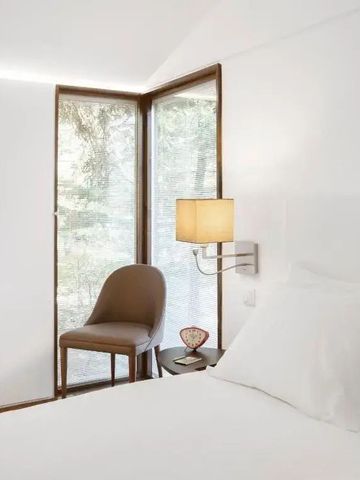 Lichtdurchflutetes Zimmer mit gemütlichem Sessel und großen Fenstern mit Blick in den Wald