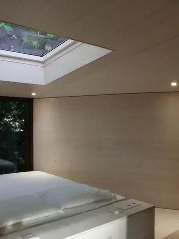 Minimalistisch eingerichtetes Schlafzimmer mit Dachfenster und Waldblick