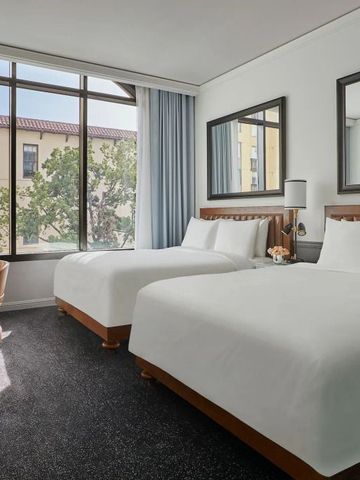 Hotelzimmer mit zwei großen Betten und großen Fenstern