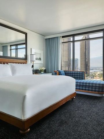 Modernes Hotelzimmer mit großem Bett und Panoramafenster mit Stadtblick.