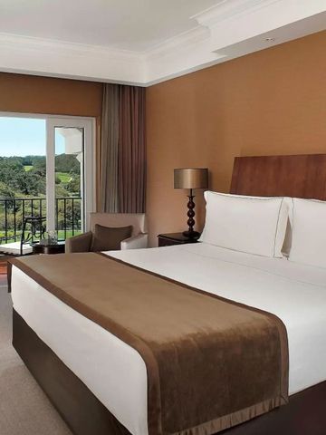 Komfortables Schlafzimmer mit braunen Akzenten und Balkon mit Blick auf die Natur