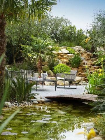 Grüner Garten mit Teich und gemütlichen Sitzgelegenheiten.