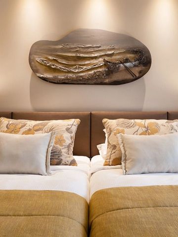 Gemütliches Hotelzimmer mit dekorativem Kunstwerk an der Wand und eleganten Kissen.