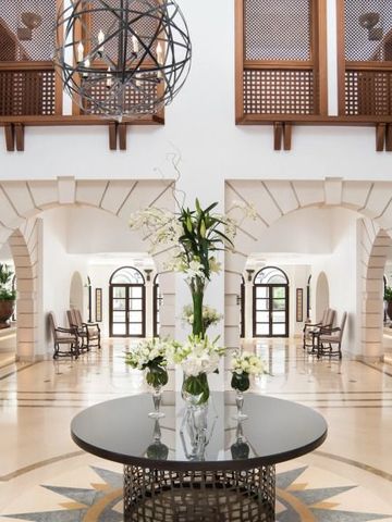 Elegante Hotellobby mit Blumen auf einem Tisch und bogenförmigen Türen.