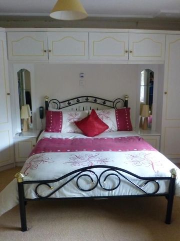 Elegantes Schlafzimmer mit eingebautem Schrank und rotem Akzent