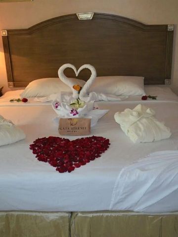 Bett mit Rosenblättern in Herzform und Handtuch-Schwänen