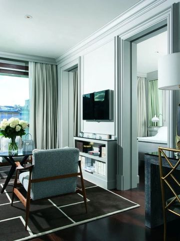 Helles Wohnzimmer in einem Hotelzimmer mit moderner Einrichtung und großer Fensterfront.