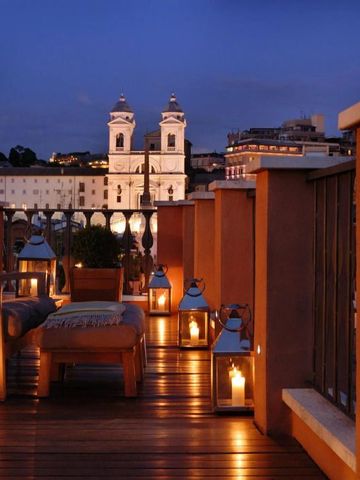 Rooftop-Terrasse mit Blick auf beleuchtete Kirchtürme im Abendlicht
