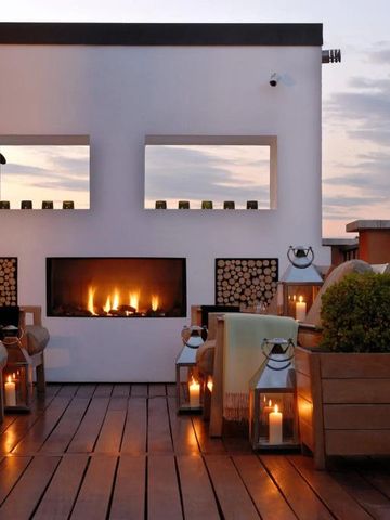 Gemütliche Terrasse mit Kamin und stimmungsvoller Beleuchtung bei Dämmerung