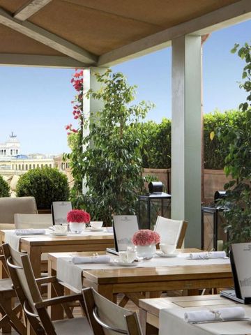 Schicke Terrasse mit gemütlichen Sitzgelegenheiten und Blick auf ein beeindruckendes Gebäude.