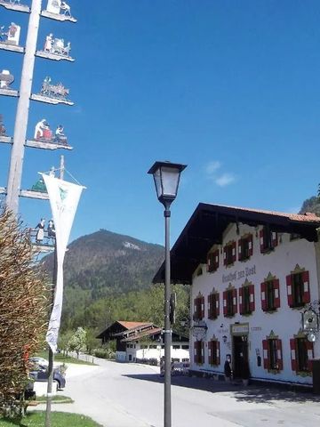 Traditionelle Hotelarchitektur mit bayerischem Maibaum im Vordergrund