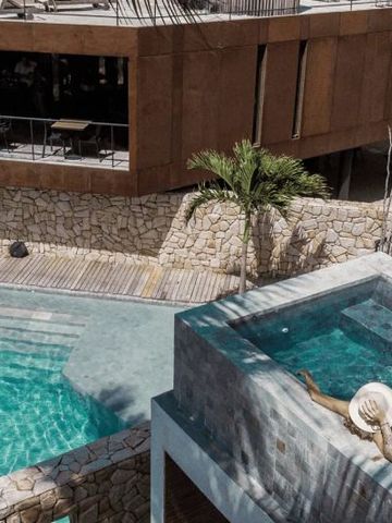 Infinity Pool und Sonnenterrasse mit Blick auf modernes Hauptgebäude.