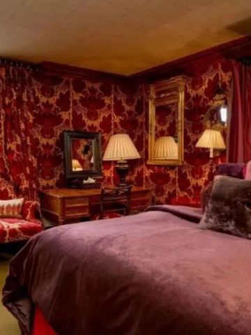 Luxuriös eingerichtetes Schlafzimmer mit rotem Samt und prächtiger Wanddekoration.