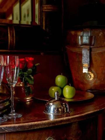 Stilvolle Getränkeecke mit Champagnergläsern und grünen Äpfeln auf antikem Möbelstück