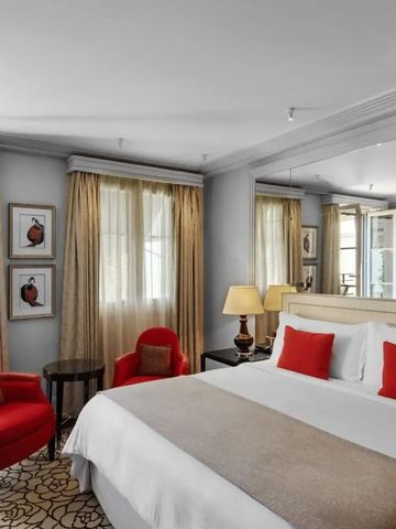 Geräumiges Hotelzimmer mit roten Sesseln und großen Fenstern