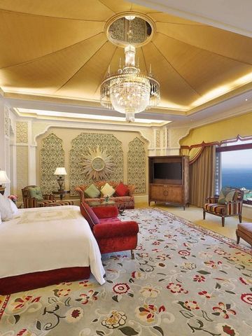 Luxuriös eingerichtete Suite mit großem Bett, eleganten Sitzmöbeln und Blick aufs Meer