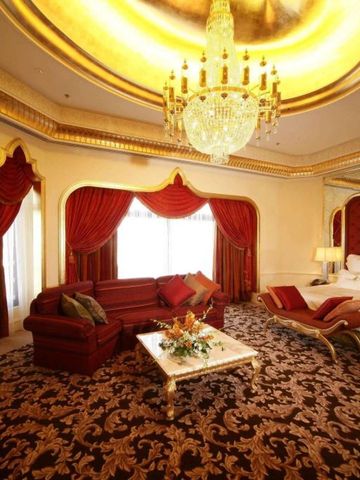 Luxuszimmer mit prunkvollem Kronleuchter und rotem Sofa im Waldorf Astoria Jeddah.