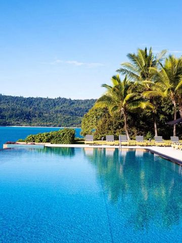 Infinity-Pool umgeben von Palmen mit Meerblick