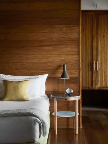 Elegantes Schlafzimmer mit Holzwänden und stilvoller Beleuchtung