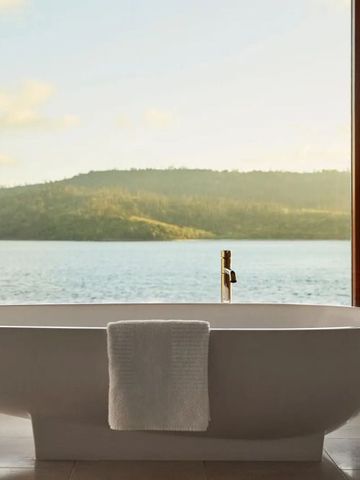 Freistehende Badewanne mit Blick aufs Meer und fernen Hügeln