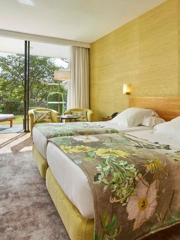 Gemütliches Hotelzimmer mit Doppelbett und Blick auf den Garten.