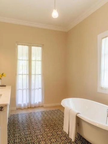 Helles Badezimmer mit freistehender Badewanne und dekorativem Bodenbelag