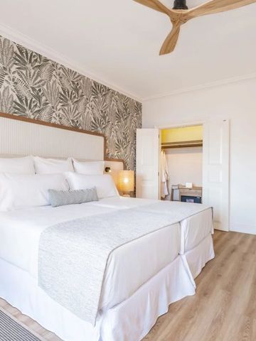 Helles und modernes Hotelzimmer mit Doppelbett und dekorativer Tapete