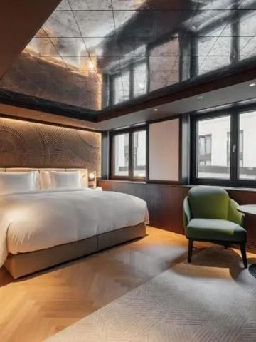 Luxuriöses Zimmer mit großem Bett, eleganter Einrichtung und Tageslicht.