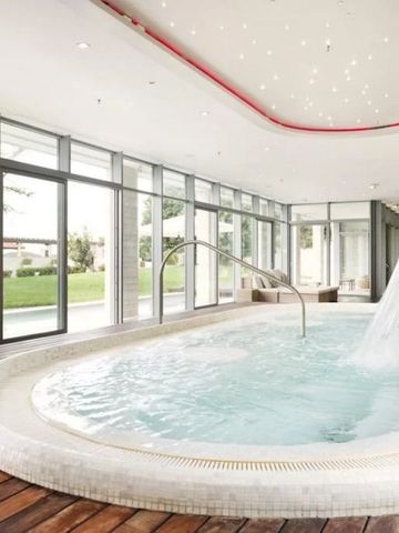 Eleganter Innenpool mit Wasserfall und großer Fensterfront mit Blick ins Grüne