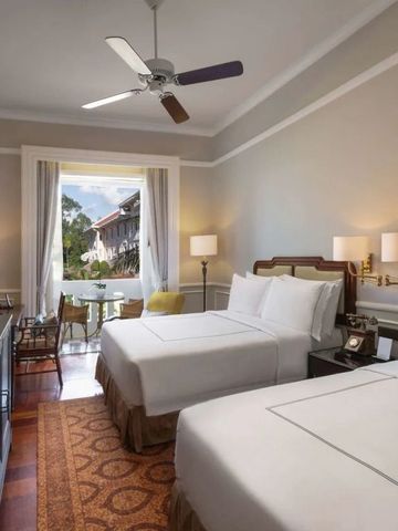 Helles Gästezimmer mit zwei Betten und Balkonblick im Raffles Grand Hotel d'Angkor