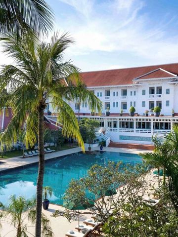 Poolbereich des Hotels mit umgebenden Palmen und dem Hotelgebäude im Hintergrund